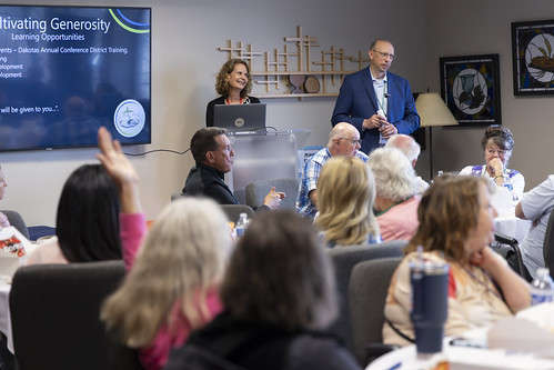 woman and man address room of people