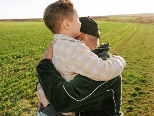 man embracing boy in field